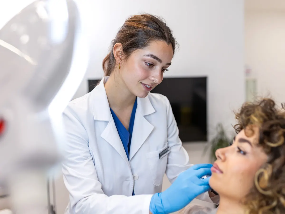 A dermatologist examining a patient's face in a clinic