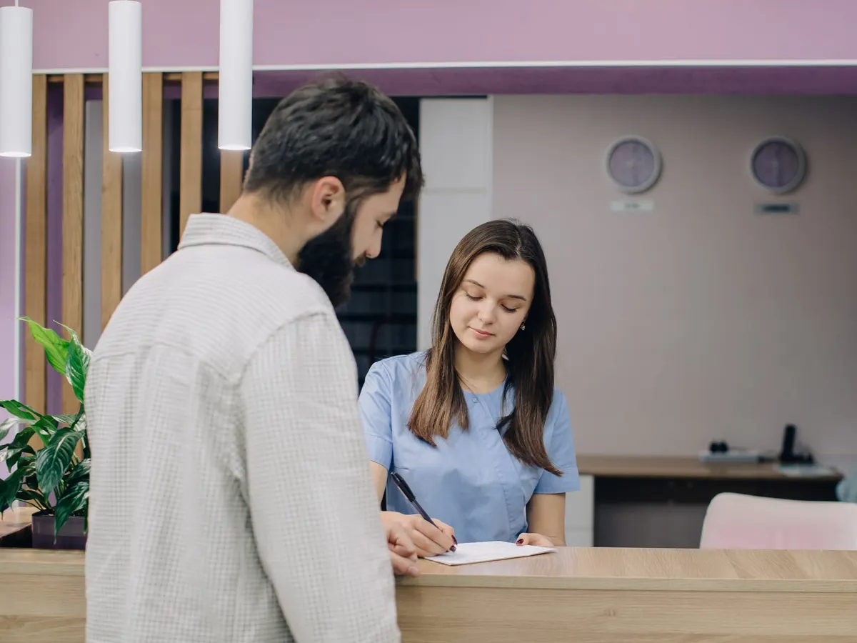 A patient signing documents at a clinic reception desk