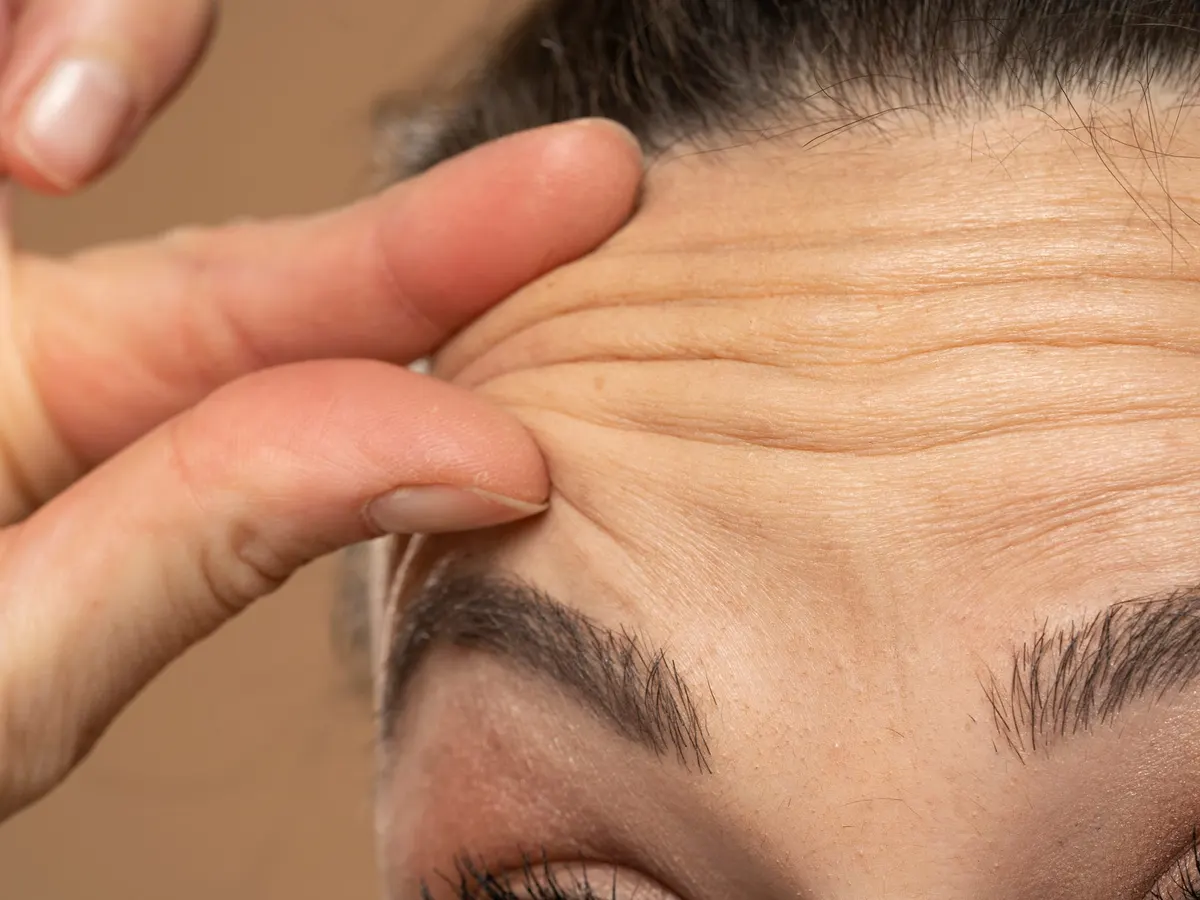 A woman smoothing the lines on her forehead