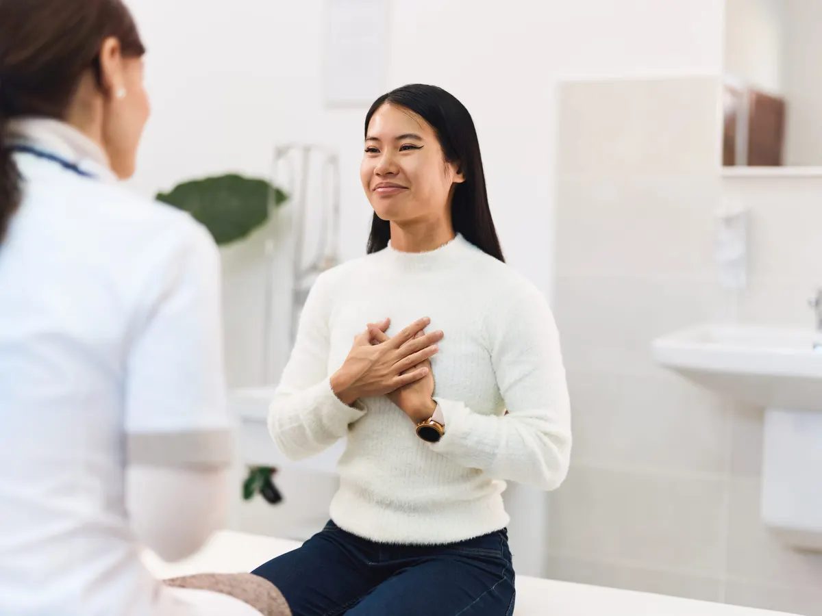 A smiling patient talking with a doctor in an examination room