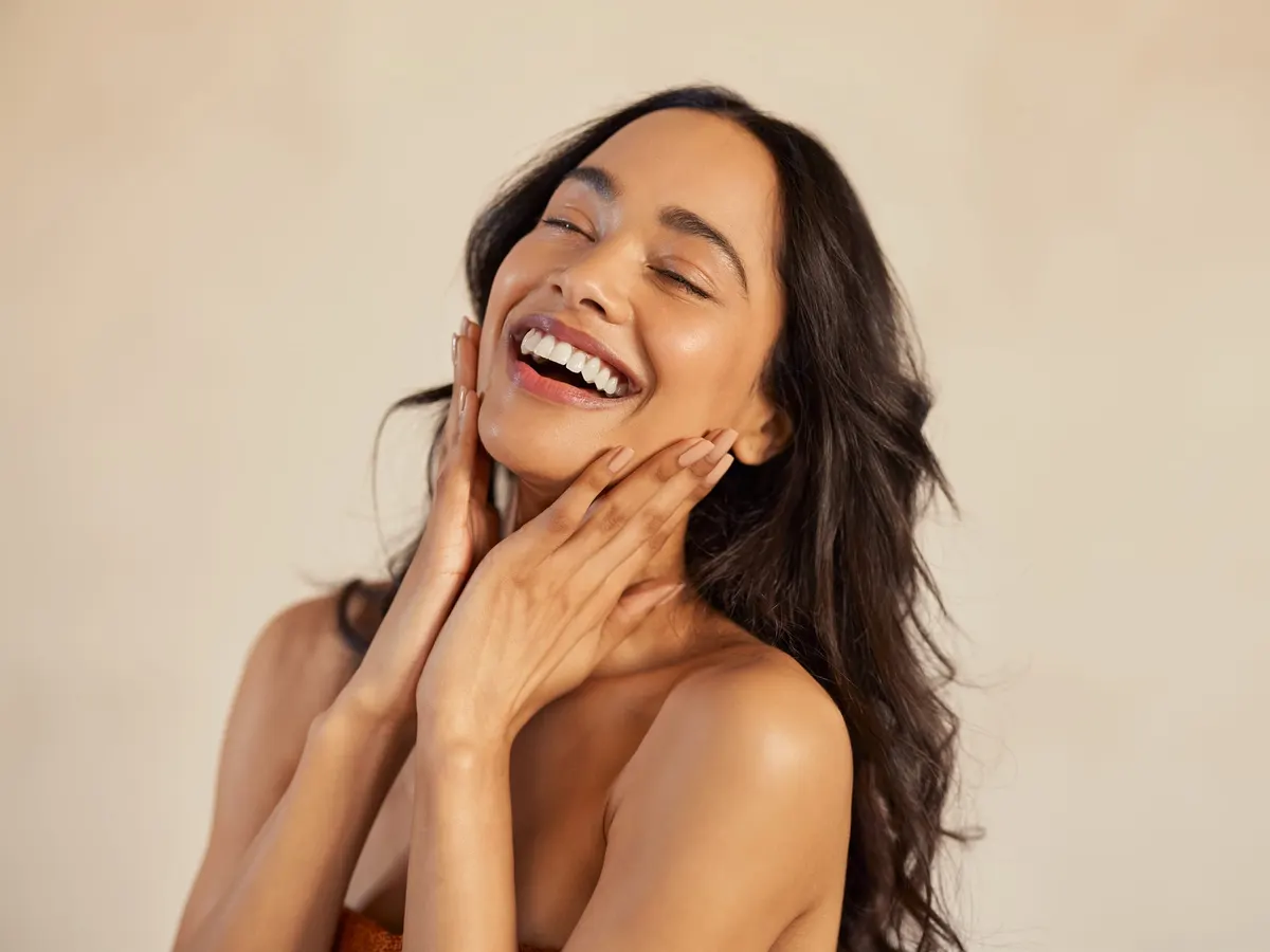 A woman laughing and touching her face