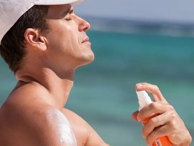 man at the beach applying protective cream