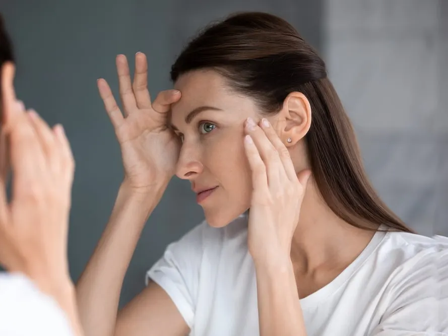 A woman with melasma looking at her skin after getting a chemical peel
