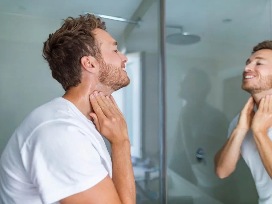 A man looking in the mirror trying to decipher between ingrown hairs vs. cysts