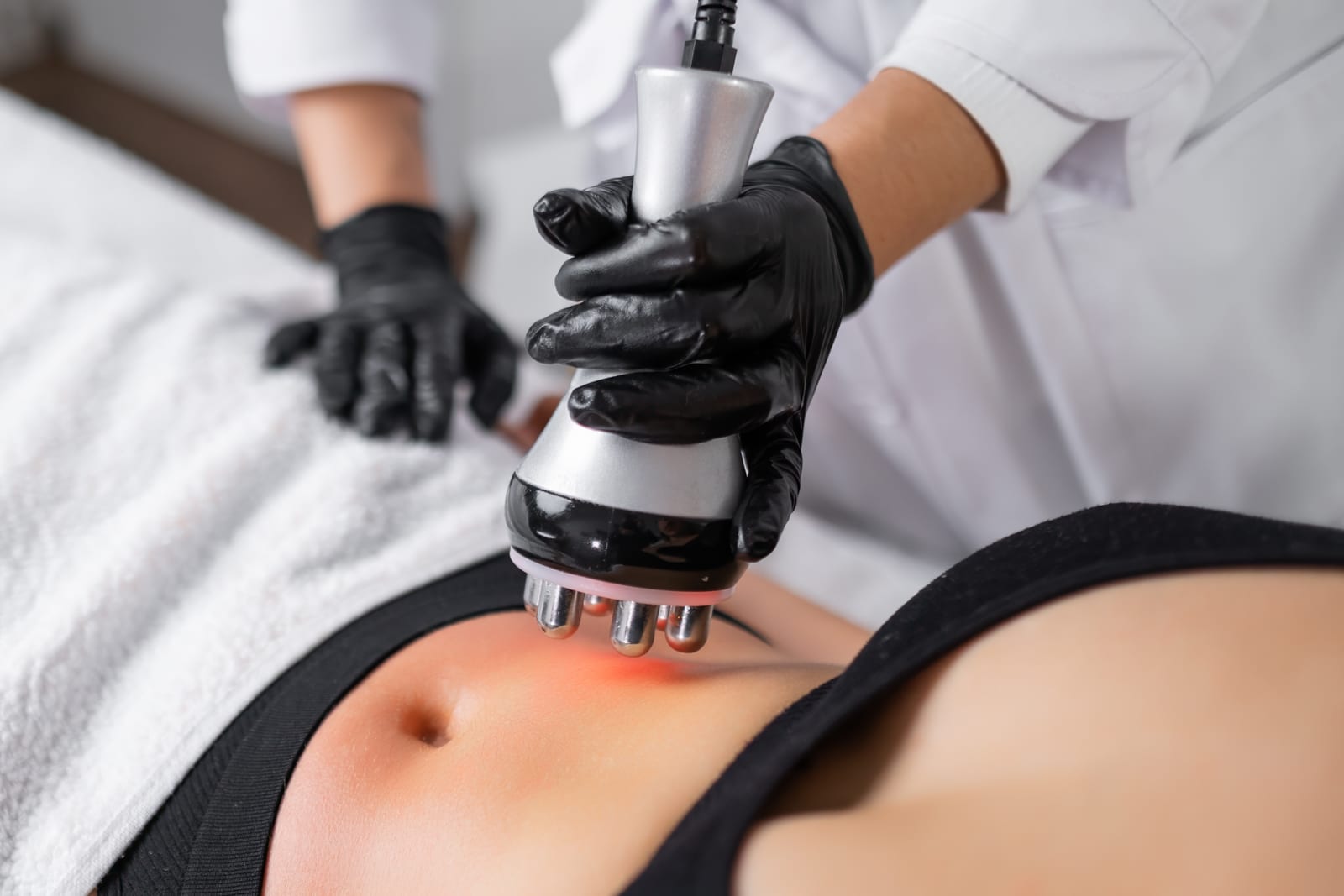 A provider uses a handheld treatment device on a patient’s abdomen