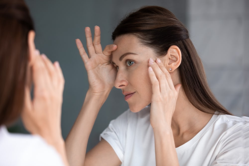 A woman with melasma looking at her skin after getting a chemical peel
