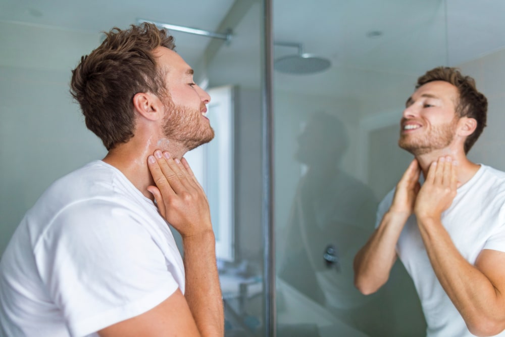 A man looking in the mirror trying to decipher between ingrown hairs vs. cysts