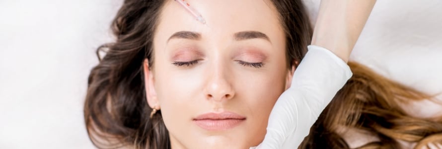 close-up image of woman's face while she receives botox injections to the forehead