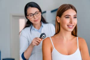 A doctor screening a woman for melanoma.
